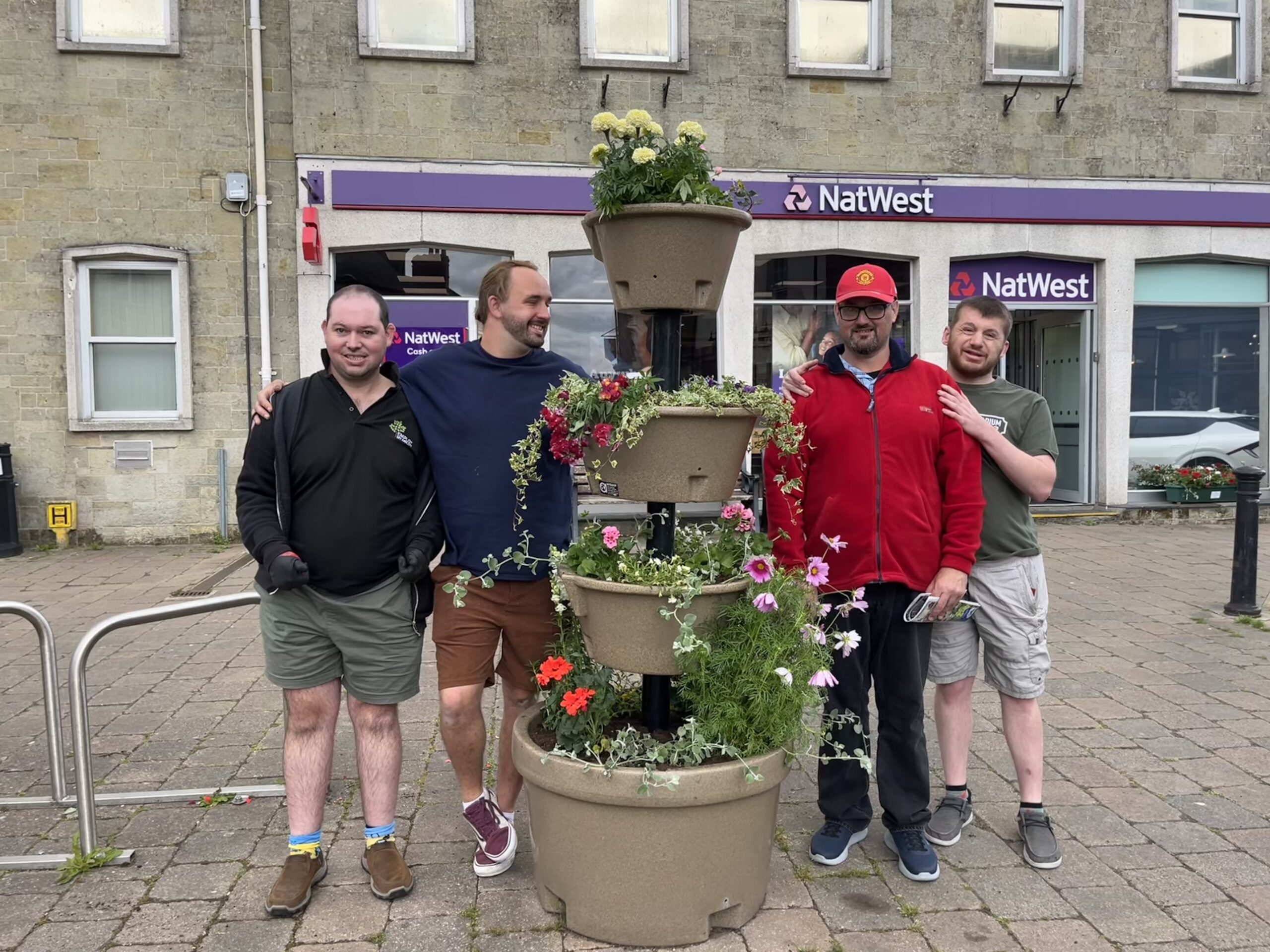 people are shown standing next to a tower of plants in a town